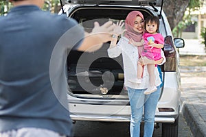 Young muslim family , transport, leisure, road trip and people concept - happy woman and little girl waving at father to say