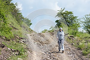 Young muslim girl wearing sport clothes walking alone on the rural mountain road