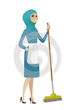 Young muslim housemaid sweeping floor with a broom