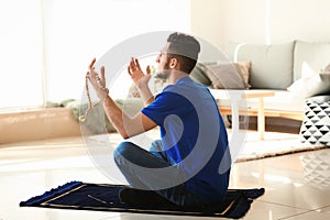 Young Muslim man praying at home