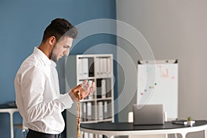 Young Muslim man praying in office