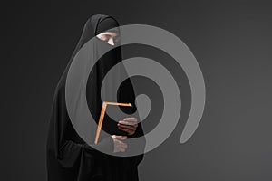 young muslim nun holding koran while