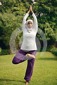 Young muslim woman doing yoga by the poolside