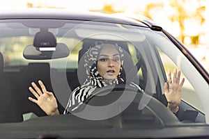 Young muslim woman driving a car shocked about to have traffic accident