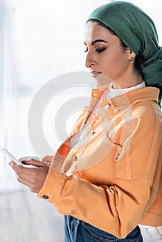 young muslim woman in headkerchief messaging photo