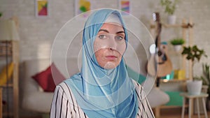 Young muslim woman in hijab with a burn scar on her face looking at the camera