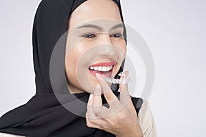Young muslim woman holding invisalign braces in studio, dental healthcare and Orthodontic concept