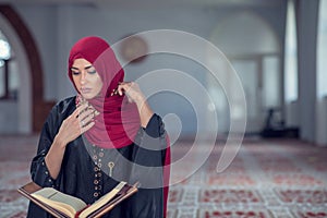 Young muslim woman praying with rosary in mosque