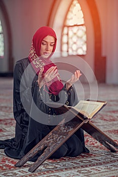 Young muslim woman praying with rosary in mosque