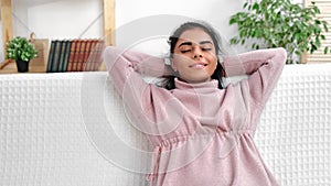 Young Muslim woman relaxing on couch home white room enjoy stress free peace moment weekend leisure