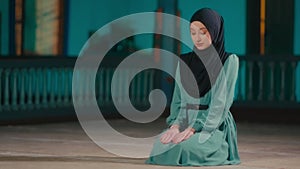 Young Muslim Woman Sitting and Then Standing Up in a Prayer in a Mosque at Night