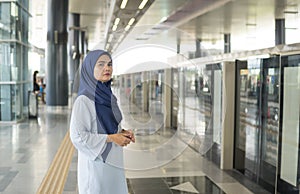 Young Muslim woman standing waiting train arrive.