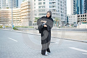 Young muslim woman in tradition Abaya clothes carrying sports bag and water bottle going to gym.