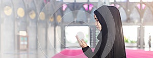 Young muslim woman in wear black dress making wish praying in mosque.