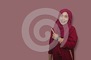 Young muslim woman wearing hijab pointing at copy space isolated on grey background