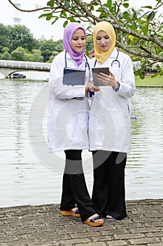 Young muslimah doctor standing and having discussion at park during lunch hour.