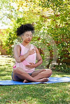 Young mutli-ethnic woman practices deep belly breathing, meditation in park