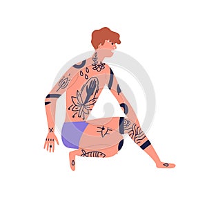 Young naked man with piercing sitting in underwear, beachwear with african black ink trendy tattoo. Body adornment