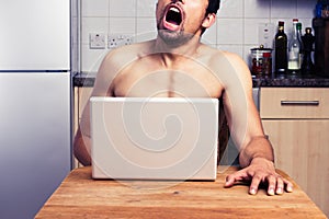 Young naked man watching in his kitchen