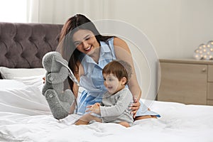 Young nanny and little baby playing with toy in bedroom photo