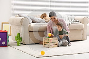 Young nanny and cute little baby playing with toys