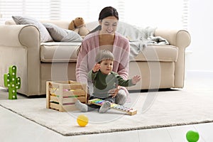 Young nanny and cute little baby playing with toys