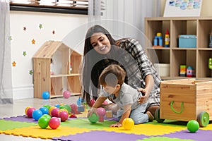 Young nanny and cute little baby playing with toys