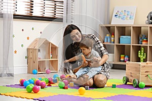 Young nanny and cute little baby playing with toys