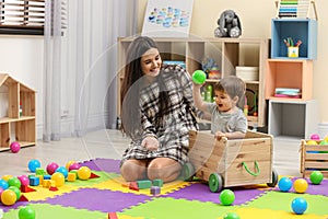 Young nanny and cute little baby playing with toys