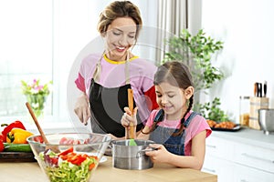 Young nanny with cute little girl cooking