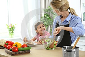 Young nanny with cute little girl cooking together