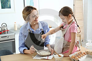 Young nanny with cute little girl cooking together