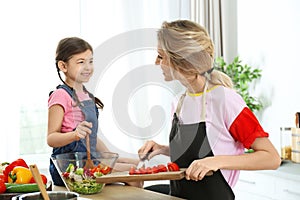 Young nanny with cute little girl cooking together
