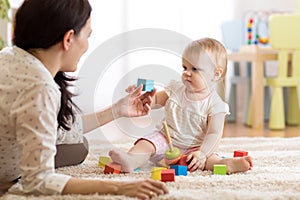 Young nanny playing with little child, indoors