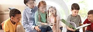 Young nanny reading book and little children. Banner design photo