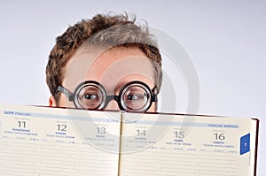 Young nerd hiding behind agenda