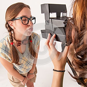 Young nerdy girls using instant camera.