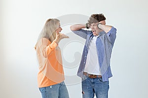 Young nervous couple wicked cute girl and upset young guy plugging ears cursing standing against white background