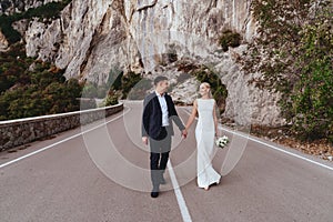 Young newly wed couple, bride and groom kissing, hugging on perfect view of mountains