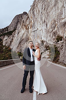 Young newly wed couple, bride and groom kissing, hugging on perfect view of mountains