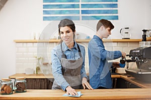 Young nice baristas in uniform working at bar counter.