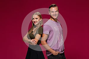 Young nice couple posing in the studio, express emotions and gestures, smiling, on a burgundy background