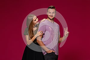 Young nice couple posing in the studio, express emotions and gestures, smiling, on a burgundy background