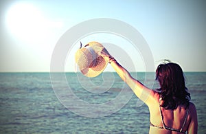 Young woman with straw hat and long hair by the opcean in summer photo