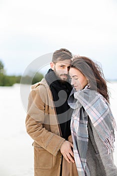 Young nice woman wearing grey scarf standing with man in coat, winter white background.