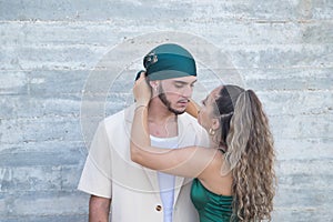 Young, non-conformist Latino and Hispanic boy and girl couple looking at each other while she ties his headscarf. Concept love,