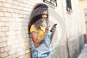 Young North African woman texting with her smart phone outdoors