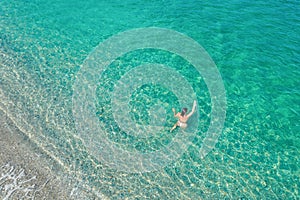 Young nude beautiful, sexy woman with naked breast lying on sea, ocean water. Summer. View from above. Top view, copter.