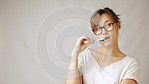 Young nurd woman in glasses nervously holding pen thinking of something