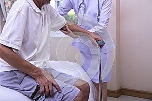 Young  nurse assisting senior man to get up from bed. Caring nurse supporting patient while getting up from bed